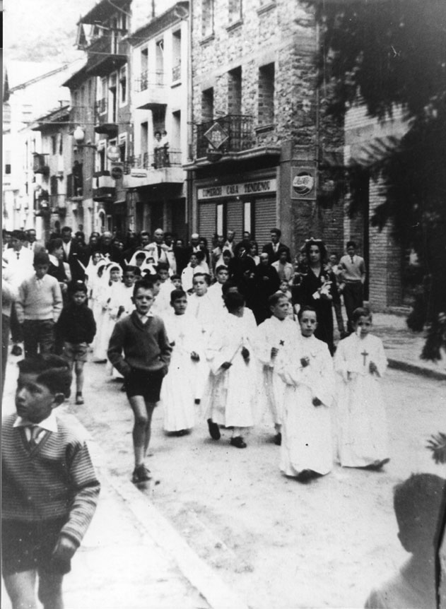 Processó de la Comunió al carrer Major. Senyora mudada: Assumpció Escobar. Nen vestit de fosc: Gascón.