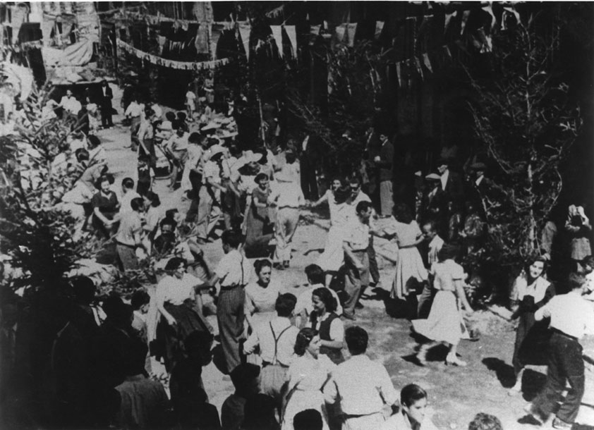 Festa major. Ball de l'esquerrana al carrer Major. Arbres per decorar el carrer durant la festa. L'Esquerrana i el Ball Pla són balls típics que encara avui es ballen, però a l'envelat.