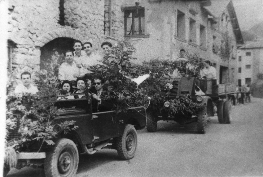 Dia de Sant Cristòfol, al carrer Major davant l'hostal Vall d'Àneu. Al cotxe asseguts: Rey, Lola Seris, Maria Borrut, Narcis Mata. Drets: Araguàs, Ramon Rey i dos nois de la Companyia.