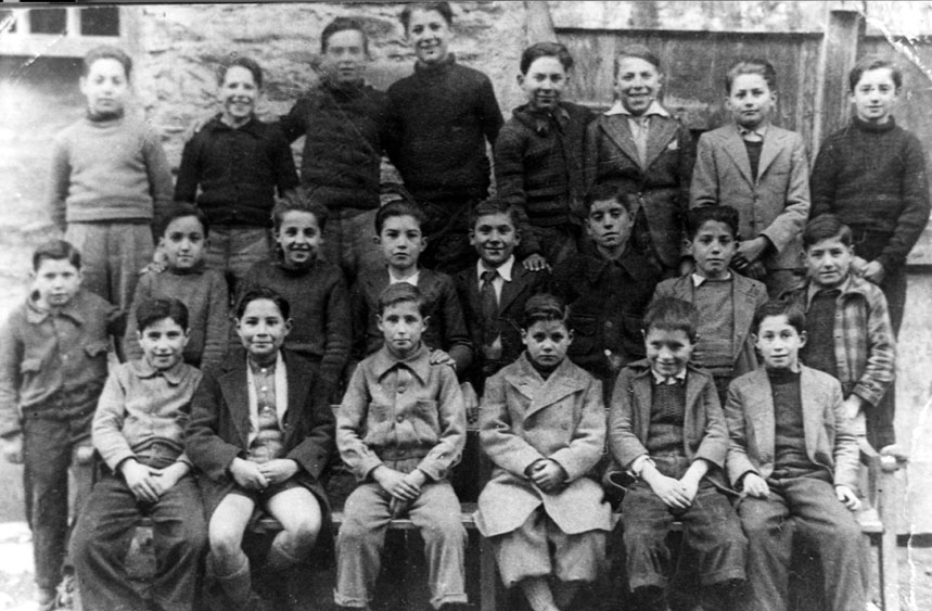 Grup escolar de nens. Personatges:
Fila Superior: Tio Balbino, Claró, Peret de Marieta, Josep M. Serra, Marcelino Costa, Pierió, Gasset, Joaquim Seria. 
Fila Central: Josep Costa, Gimi, Arcadi Mir, ?, Angel Quiquen, Victor Meleta, Josep Beso, Joan Castellarnau, Joanblau del Camp.
Fila Inferior: Antonio Solé, Josep Vigatà, Marxant de França Josep Montané, Guillermo Gasset, Paquito Cadiraire, Josep Birbe.