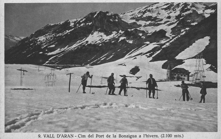 Esquiadors al cap del port de la Bonaigua amb el xalet-refugi de la Canadenca al fons.