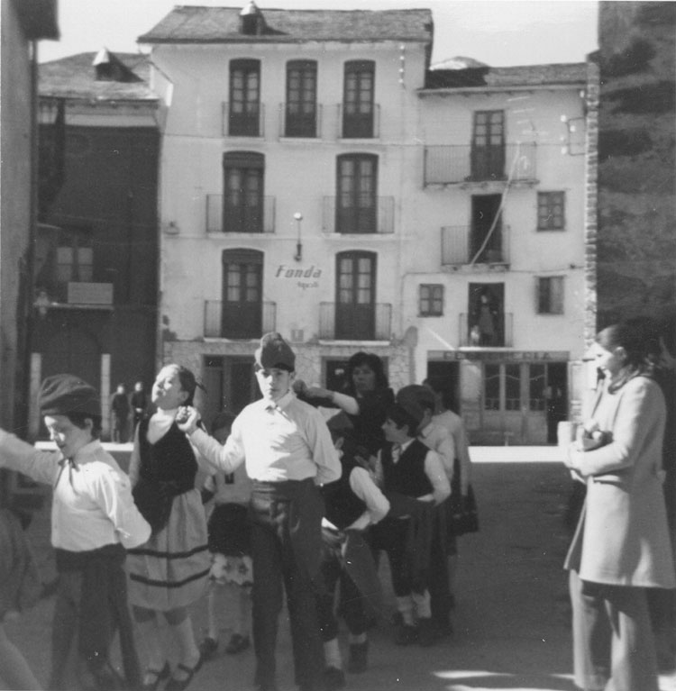 Nens del col·legi d'Esterri el Dijous Gras ballant a la plaça de la Fonda Agustí. Al costat de la Fonda hi havia la Barberia Jaume.