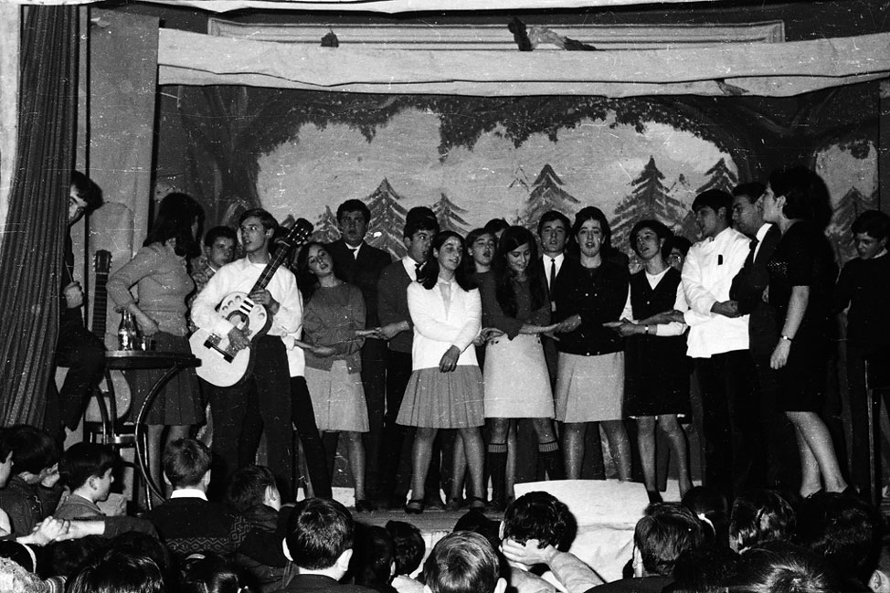 Festival de Nadal a casa Agustí. Rafel Muniesa tocant la guitarra, Paloma de la Guingueta, Mercè de Gorró, Josep de Gorró, Lluís Tendenou, Margarita de Carinyo, Carmen Lucia soto, Cati de Don Raimundo de la Guingueta, Jaume de Cabirol, Ignasieta de Marxant, Trini de Miqueu, Pedro de Sumastre, Tono López, Xelo Olave i Josep de Casterlenes.