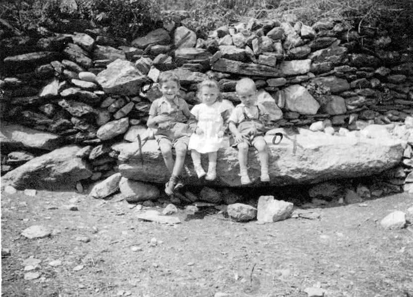 Grup de nens assentats sobre una pedra. D'esq. Fco de Casa mossèn Joan, Joana Maria de Casa Roya y Juanito de Casa Mossèn Joan.